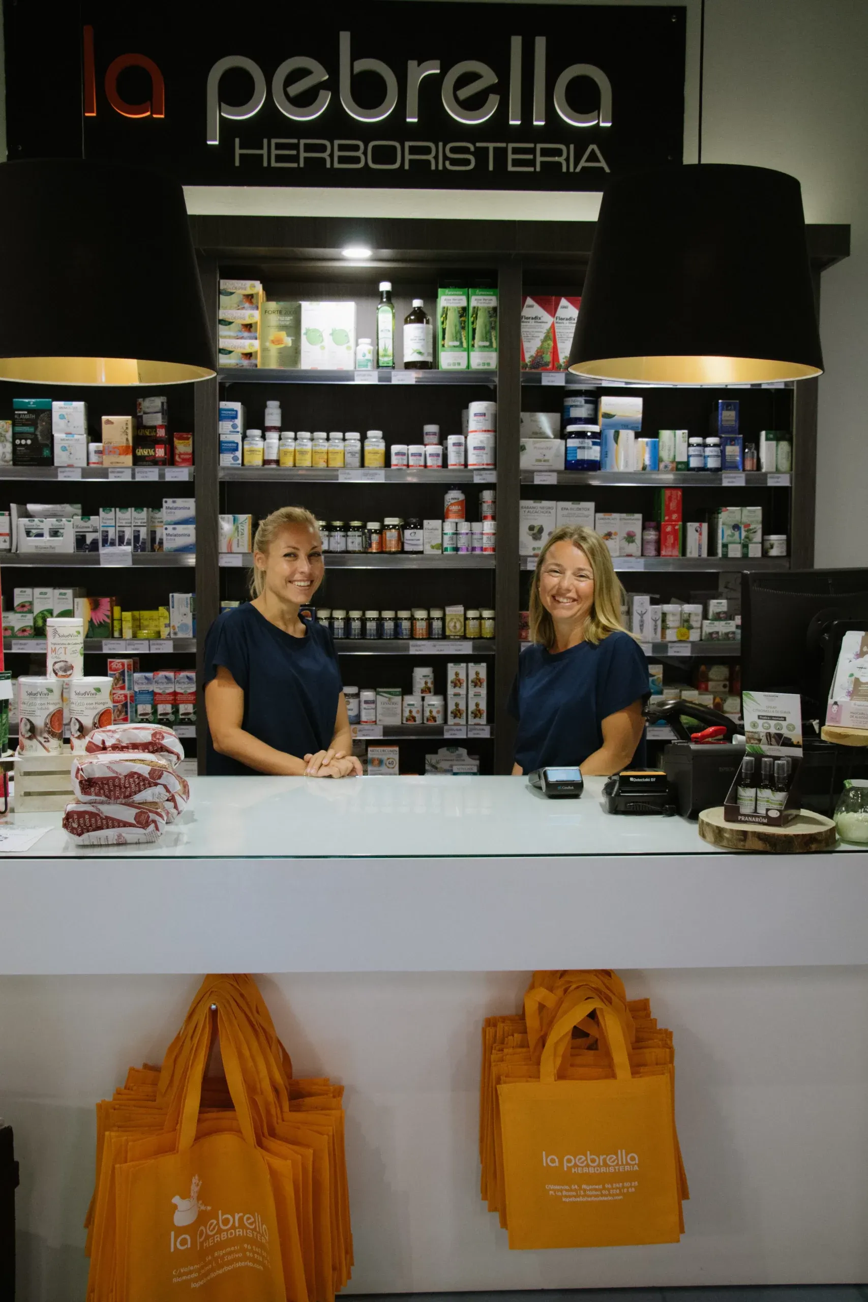Las dependientas de La Pebrella sonriendo tras el mostrador de la tienda